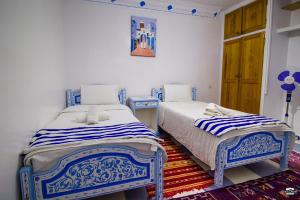 two beds in a room with blue and white at Casa Voyager 'secret garden terrace' in Chefchaouen