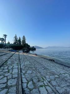 a cobblestone beach with people on it next to the water at Appartamento sul Lago - MEINA in Meina