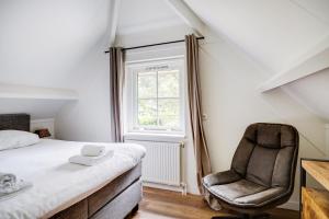 a bedroom with a bed and a chair at Comfortabel vakantiehuis in het bos op de Veluwe in Lunteren