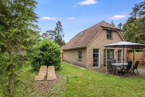 a small house with a table and an umbrella at Comfortabel vakantiehuis in het bos op de Veluwe in Lunteren