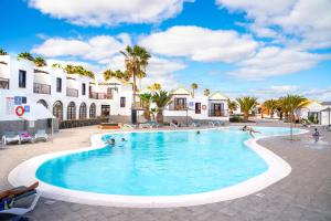 a large swimming pool in a resort with palm trees at Elite Fuerteventura by Ecr in Caleta De Fuste