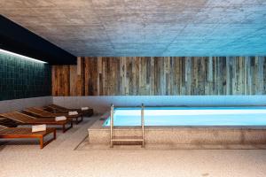 a large swimming pool with a blue ceiling and benches at Runo Apartamenty & SPA - Basen Sauna - Odkryj-Białkę in Białka Tatrzańska
