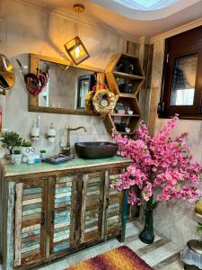 a bathroom with a sink and a vase with pink flowers at Speranza's Sweet Home in Vrontados