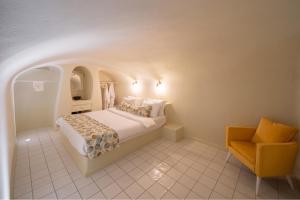 a bedroom with a bed and a yellow chair at Luna Santorini Suites in Pirgos +64 photos