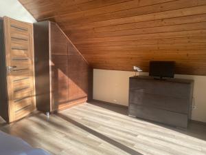 a room with a wooden ceiling and a tv on a cabinet at Jarski Domek in Stężyca