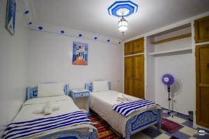 a bedroom with two beds and a lamp in it at Casa Voyager 'secret garden terrace' in Chefchaouen