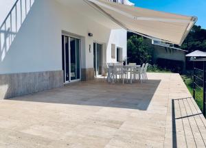 a patio with a table and chairs under a white umbrella at Hauzify I Casa Gaditana in Santa Cristina d'Aro