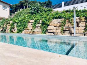 a swimming pool with a rock wall next to a house at Hauzify I Casa Gaditana in Santa Cristina d'Aro +16 photos