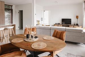 a living room with a wooden table and chairs at Brand New Apartment Sint-niklaas in Sint-Niklaas +30 photos