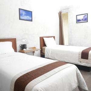 ein Hotelzimmer mit zwei Betten und einem Fenster in der Unterkunft Bale Karang Cottages in Batukaras