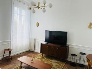 a living room with a flat screen tv on a cabinet at Appartement Porte Mars 1 Reims Arena gare centre in Reims +12 photos