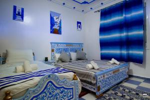 two beds in a room with blue and white at Casa Voyager 'secret garden terrace' in Chefchaouen