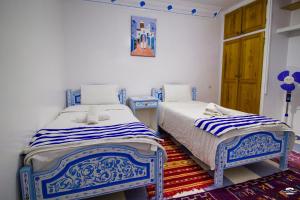two beds in a room with blue and white at Casa Voyager 'secret garden terrace' in Chefchaouen