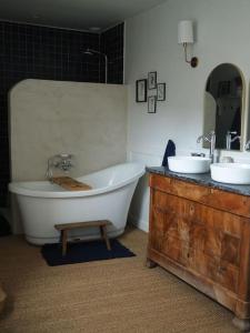 ein Badezimmer mit einer Badewanne und zwei Waschbecken und einem Holztisch in der Unterkunft Charmante Grange aux Monts d'Or in Collonges-au-Mont-dʼOr