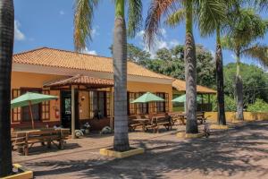 un edificio con mesas de picnic y palmeras en Hotel Fazenda Primavera da Serra, en Brotas