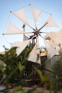 a windmill with white sails in front of a house at Mylos Home in Analipsi