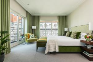 a bedroom with a bed and a chair and windows at Rocco Forte The Charles Hotel in Munich