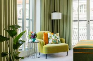 a living room with a yellow chair and a table at Rocco Forte The Charles Hotel in Munich