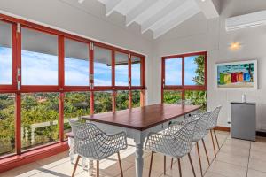 a dining room with a table and chairs and windows at San Lameer Villa - 14306 - 5 Bedroom Luxury - 10 pax - San Lameer Rental Agency in Southbroom