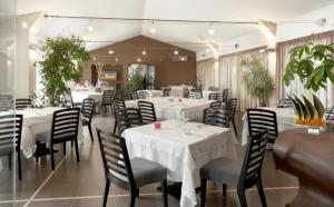 restauracja z białymi stołami, krzesłami i roślinami w obiekcie Casato Licitra w mieście Donnafugata
