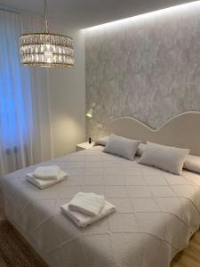 a white bedroom with a large bed with towels on it at El Sueño de Luca, Parking gratuito centro in Logroño