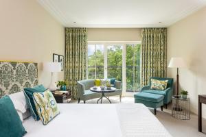 a bedroom with a bed and two chairs and a window at Rocco Forte The Charles Hotel in Munich