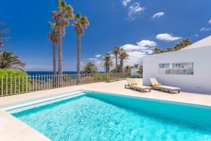 a swimming pool with palm trees and a house at Ocean Bliss Beautiful Villa with Pool and Sea Views in Costa Teguise