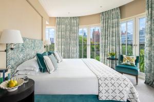 a bedroom with a large bed and a large window at Rocco Forte The Charles Hotel in Munich