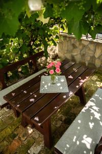 a wooden bench with a table with flowers on it at Római Home in Hévíz