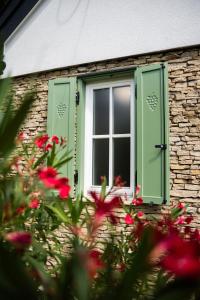a window with green shutters on a brick building with flowers at Római Home in Hévíz +17 photos