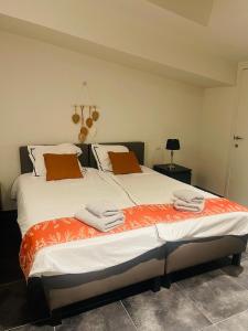 a bedroom with two beds with orange and white sheets at Equus B&B in Bredene +25 photos
