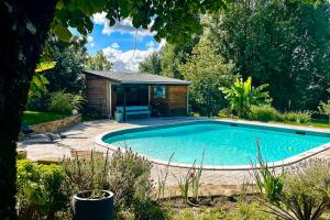 una piscina in un giardino con un capanno di Gîte Les Dalias a La Porcherie