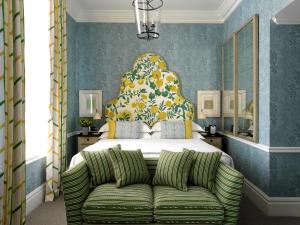 a bedroom with a bed with a green couch at Covent Garden Hotel, Firmdale Hotels in London