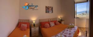 a bedroom with two beds with orange sheets and a window at Casa Marea Sperlongaresort apartment in Sperlonga