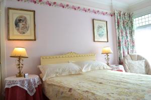 a bedroom with a bed and two lamps and a chair at Knightsrest in Burnham on Sea