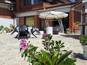 a patio with two chairs and an umbrella and flowers at Green House in Terracina