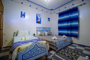 two beds in a room with blue and white at Casa Voyager 'secret garden terrace' in Chefchaouen