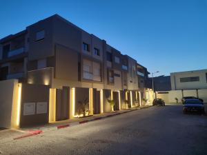 un edificio con luces en el lateral de una calle en Coquet appartement avec piscine à 10min de l'aéroport Tunis - family only, en La Soukra