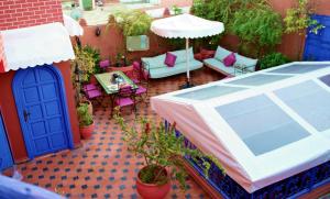 un patio al aire libre con sombrilla, mesas y sillas en Riad Konouz, en Marrakech
