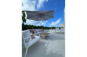 a patio with an umbrella and a couch and tables at ZenBreak The Nest 3bd in Saint James