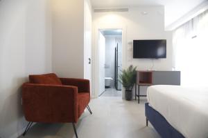 a bedroom with a bed and a chair and a television at Stylish Modern Studios - Port & Beach Apartments, Haifa in Haifa