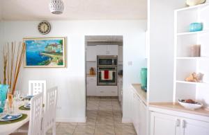 a kitchen and dining room with white cabinets and a table at ZenBreak Silver Sands Villa 3 in Christ Church