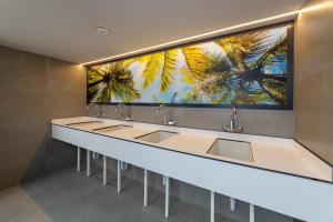 a bathroom with sinks and a large painting of palm trees at Camping Villasol in Benidorm