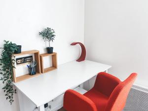 a white desk with a red chair and plants at Studio à 10 mins de Paris in Rosny-sous-Bois