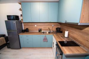 a kitchen with blue cabinets and a sink and a refrigerator at Benny's flat in Stara Zagora +3 photos