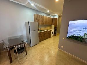 a kitchen with a refrigerator and a table and a tv at Bakva's apartment in Batumi