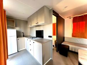 a kitchen with white cabinets and a white refrigerator at Camping Village Tuscia Tirrenica in Tarquinia