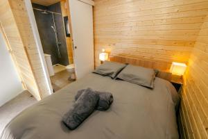 a bed in a room with a wooden wall at Le Laponya - Chalets climatisés avec SPA & Borne de recharge in Bressols