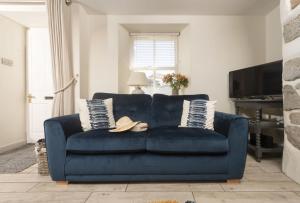 a blue couch in a living room with a tv at Oriel Cottage in St. Agnes