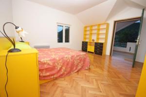 a bedroom with a yellow bed and a wooden floor at Duplex apartman Petrović in Franciskovići
